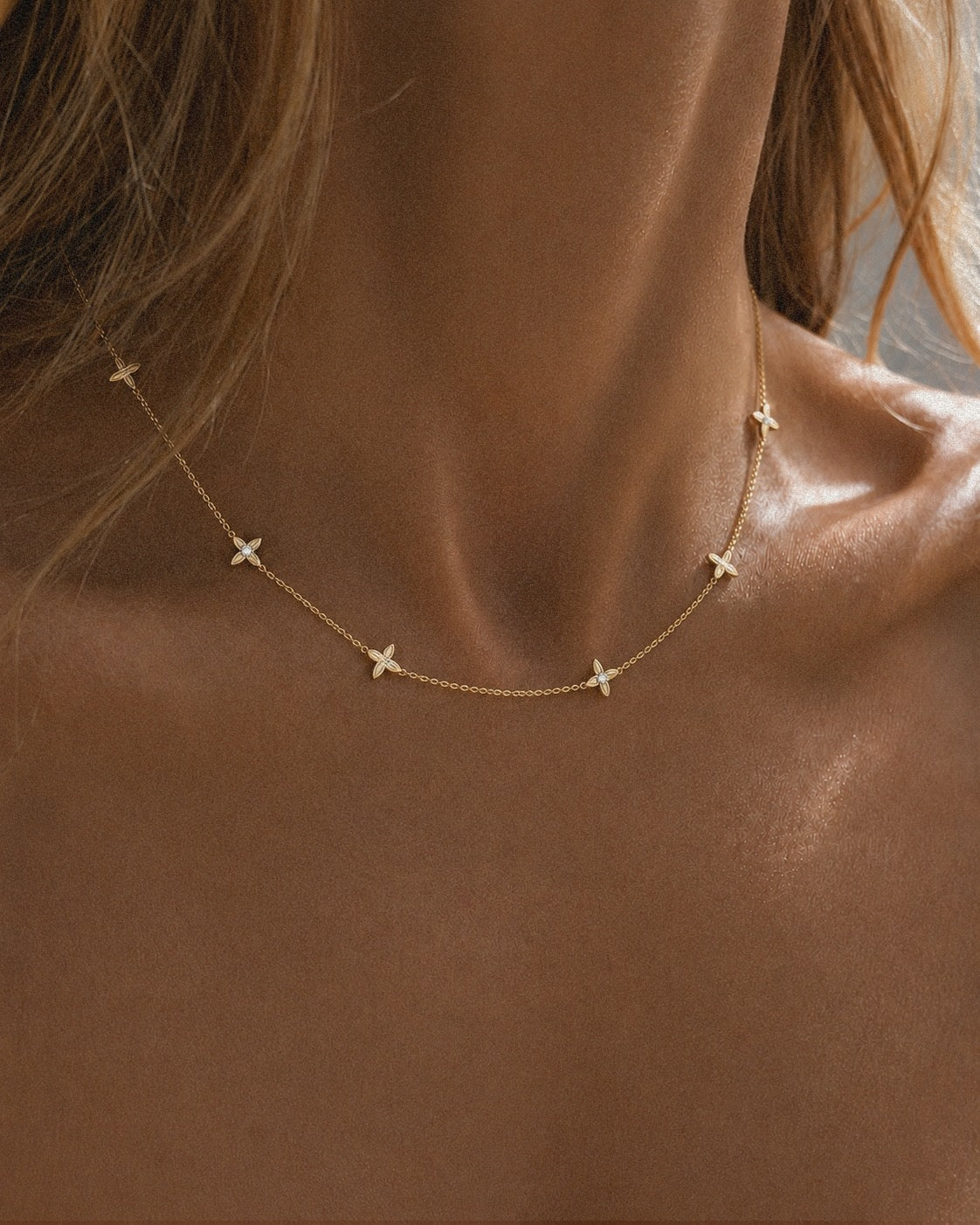 The Flora Station Necklace in recycled 18K gold, worn at the neckline.