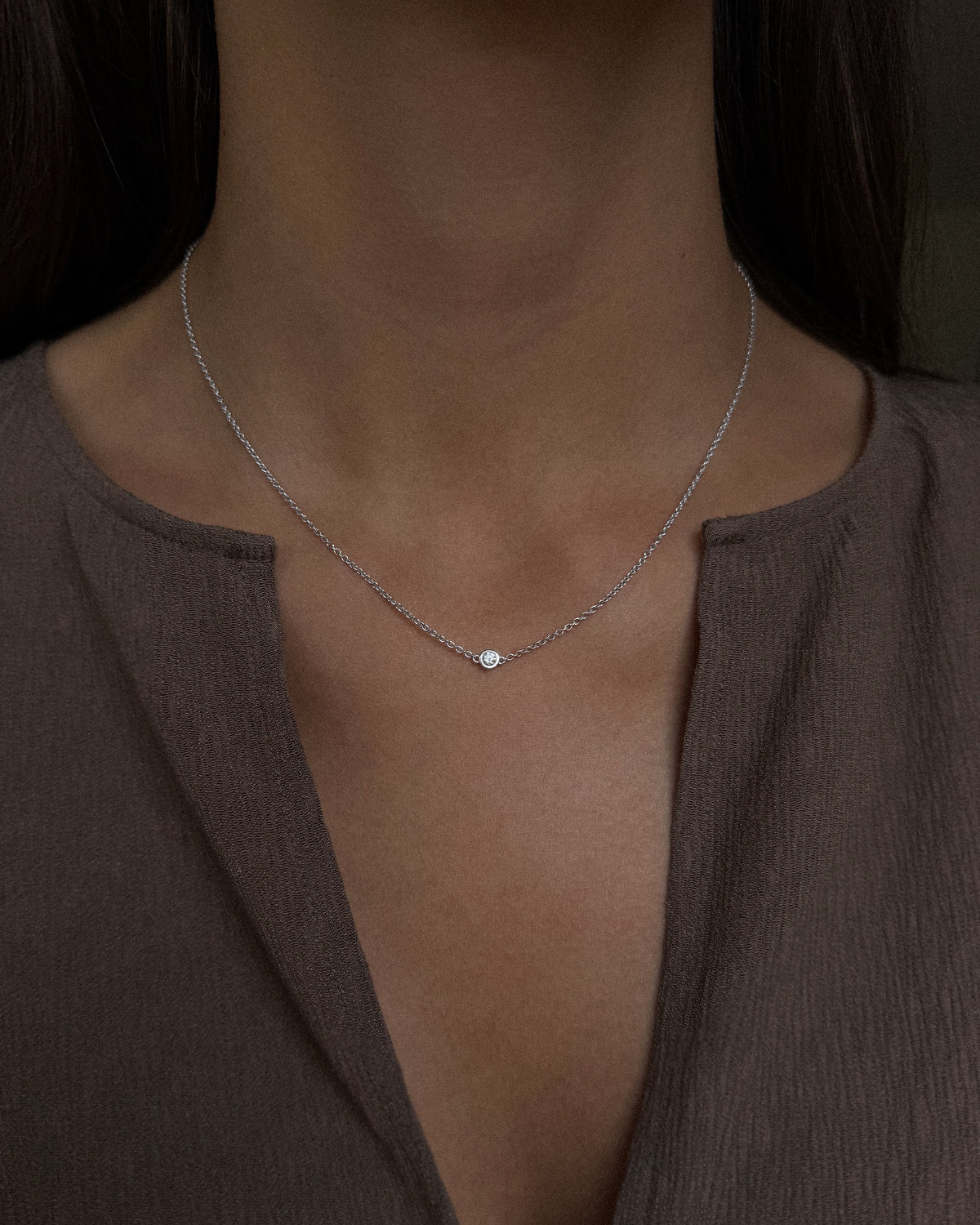 The Bezel Diamond Necklace in recycled 18K white gold, worn at the neckline.