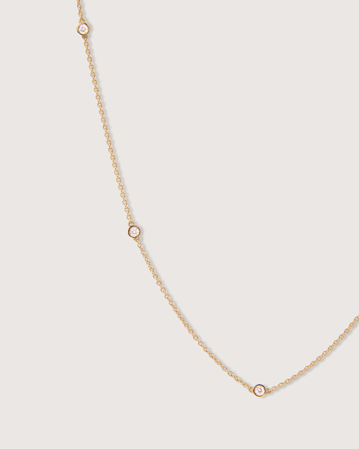 The Bezel Diamond Station Necklace in recycled solid 18K gold, set with five bezel-set diamonds spaced along the chain.