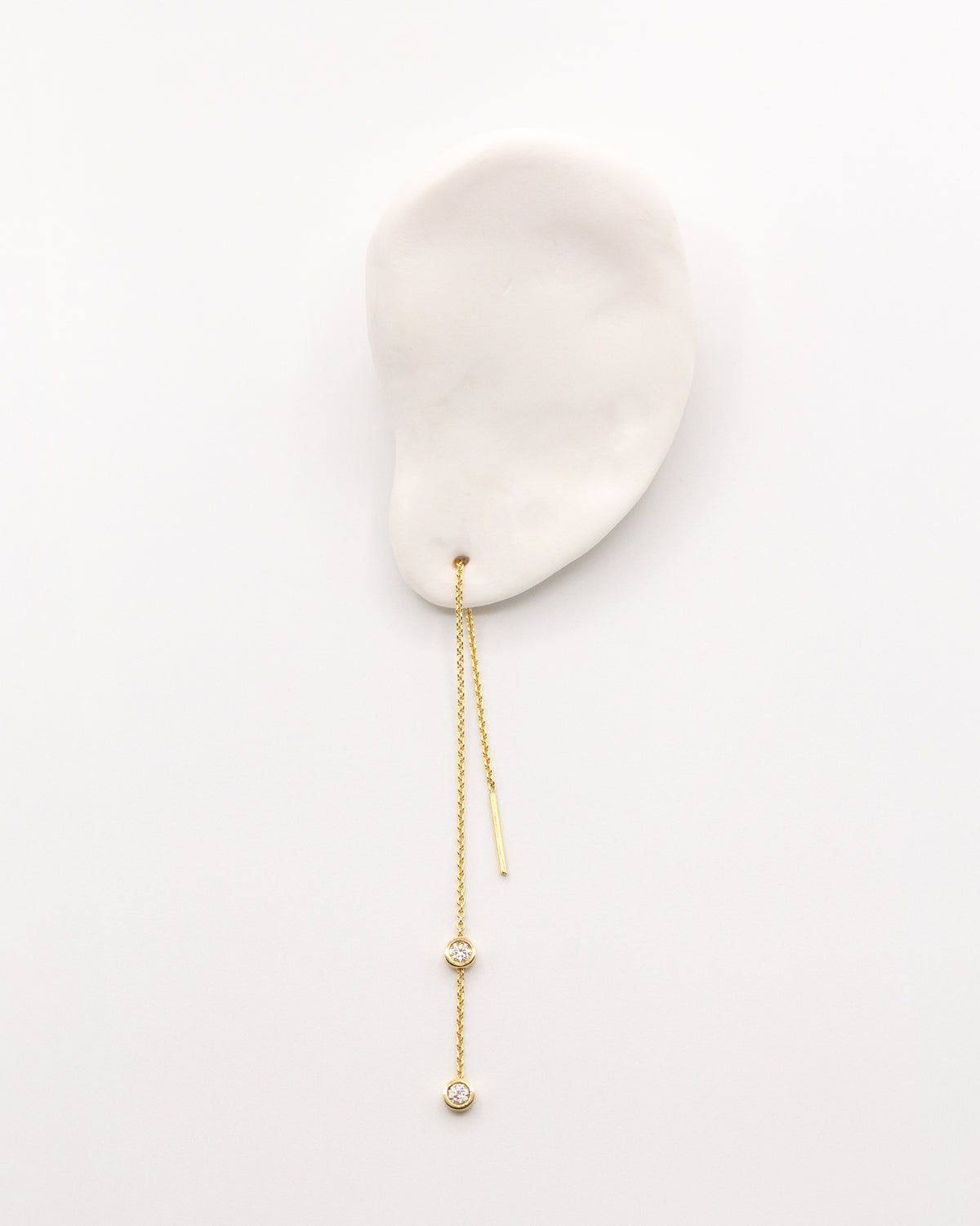 The Diamond Threader Earring in recycled solid 18K gold, set with two bezel-set lab-grown diamonds.
