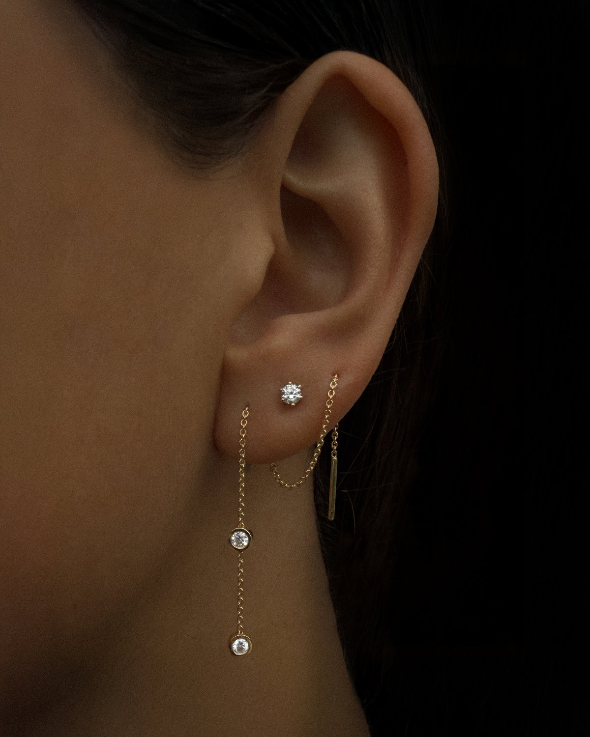 The Diamond Threader Earring in recycled 18K gold, worn threaded through the ear.