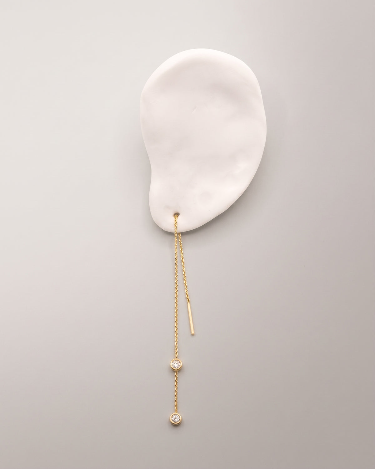 The Diamond Threader Earring in recycled solid 18K gold, set with two bezel-set lab-grown diamonds.