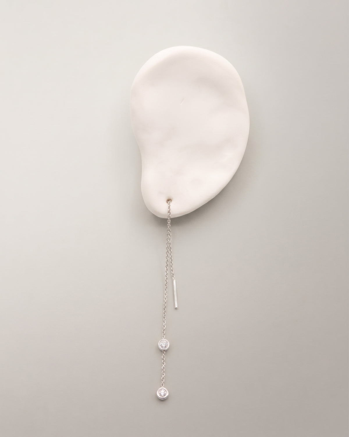 The Diamond Threader Earring in recycled solid 18K white gold, set with two bezel-set lab-grown diamonds.